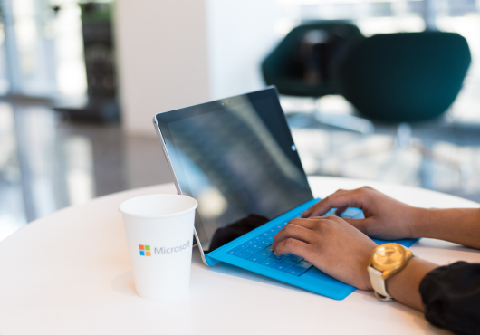 Kvinna vid laptop med mugg från Microsoft